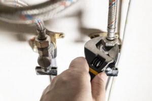 plumber hand fixes connection of tap by wrench