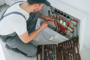 With special tools. Repairman is working indoors in the modern room